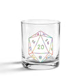A clear glass rocks tumbler featuring a colorful, rainbow-lined 20-sided die (D20) graphic with its numbers printed in various hues, set against a plain white background.